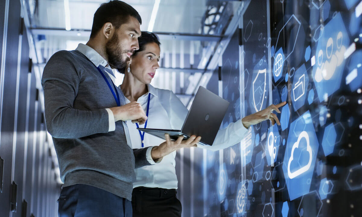 Two IT professionals analyzing cloud computing and network infrastructure on a digital interface using a laptop