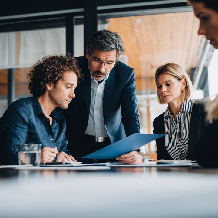 Business professionals collaborating and reviewing documents in a meeting, discussing strategy and decision-making in an office environment