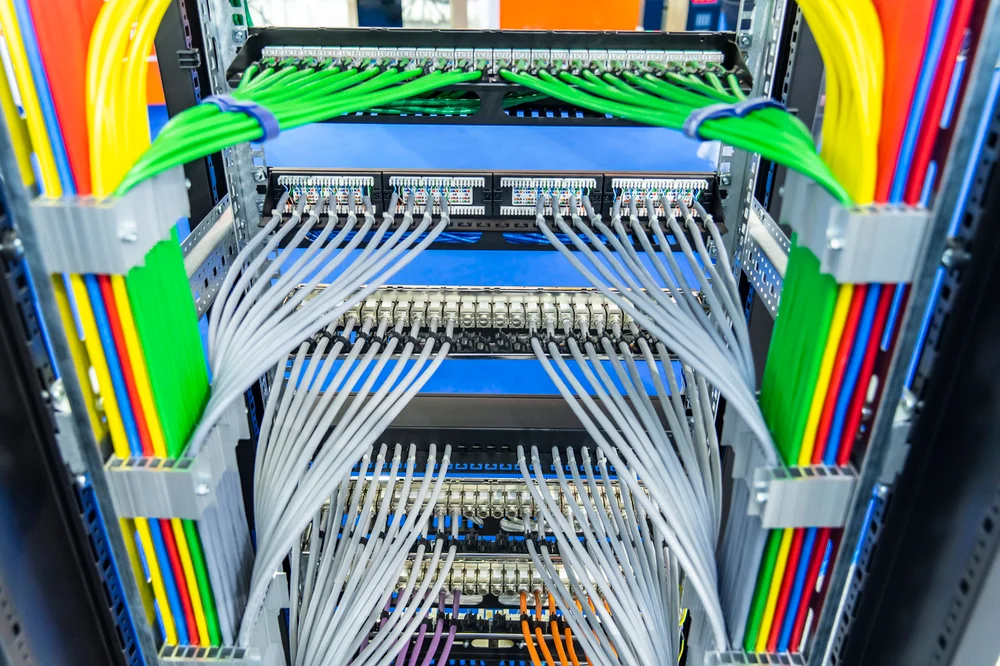 Well-organized server rack with structured cabling, patch panels, and color-coded fiber and Ethernet cables for efficient network management